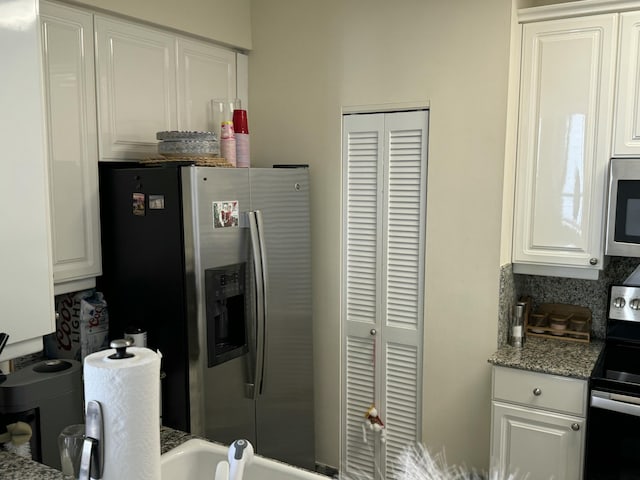 kitchen with appliances with stainless steel finishes, stone countertops, white cabinetry, and backsplash