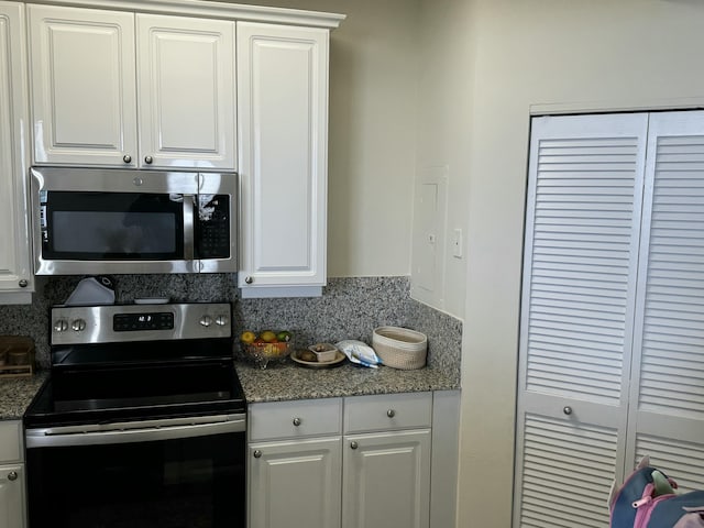 kitchen with appliances with stainless steel finishes, white cabinets, and backsplash