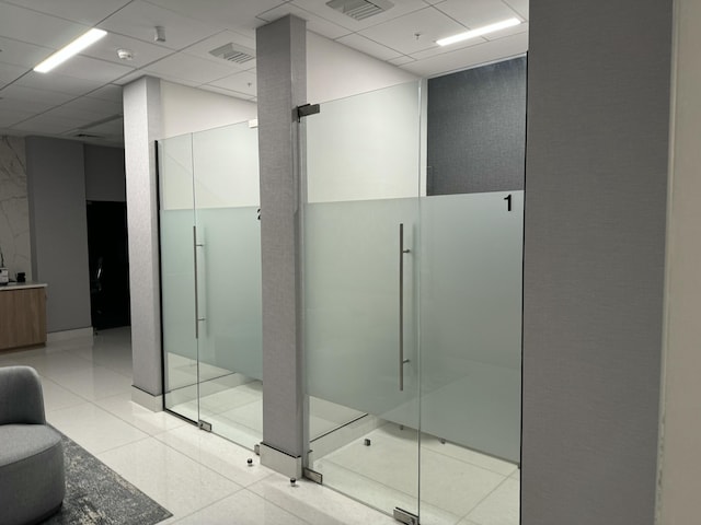 bathroom featuring a paneled ceiling, a shower stall, visible vents, and tile patterned floors