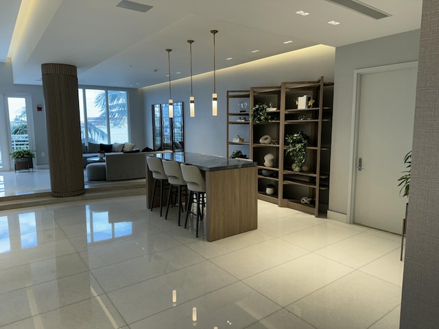 kitchen featuring a breakfast bar area, light tile patterned floors, hanging light fixtures, open floor plan, and a kitchen island