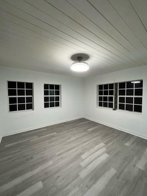 unfurnished room with baseboards, wood finished floors, and wooden ceiling