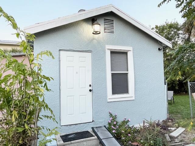 doorway to property with fence and stucco siding