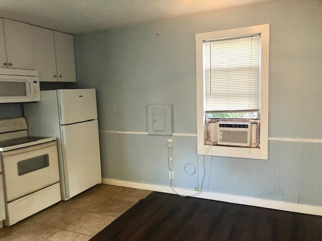 1831 Juno Rd Unit 123, North Palm Beach, FL 33408 - kitchen with white appliances, baseboards, cooling unit, and wood finished floors