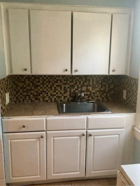 1831 Juno Rd Unit 123, North Palm Beach, FL 33408 - kitchen featuring a sink, decorative backsplash, white cabinetry, and light countertops