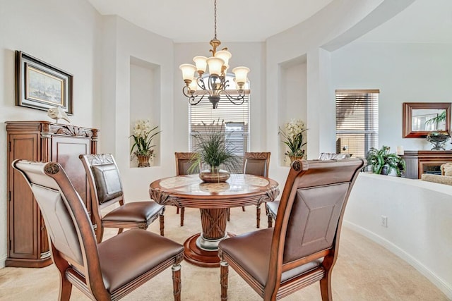 dining space with baseboards, light carpet, and a chandelier