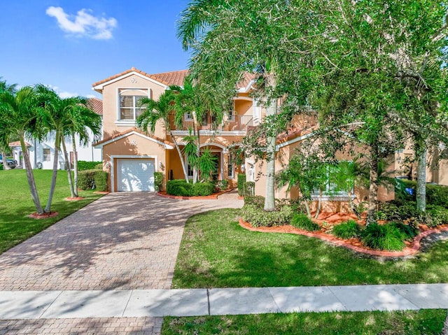 mediterranean / spanish house featuring a front yard, a balcony, stucco siding, a tiled roof, and decorative driveway