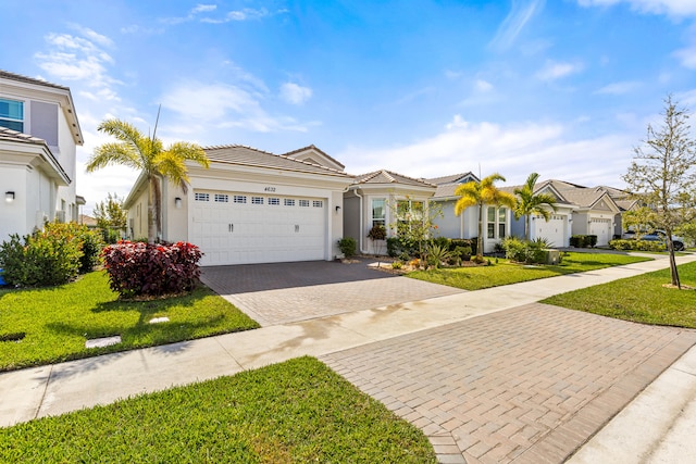 view of front of home featuring stucco siding, a front lawn, a tile roof, decorative driveway, and a garage