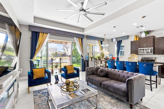 living room with visible vents, a ceiling fan, baseboards, light tile patterned floors, and a raised ceiling