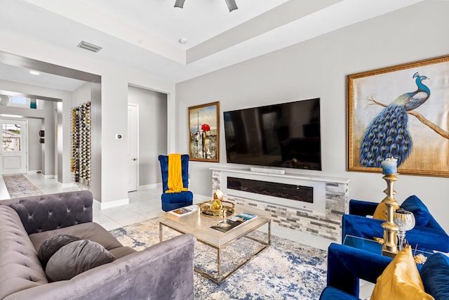 tiled living room with visible vents, baseboards, and a glass covered fireplace