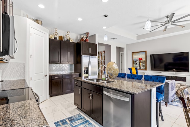 kitchen featuring open floor plan, appliances with stainless steel finishes, marble finish floor, stone countertops, and a sink