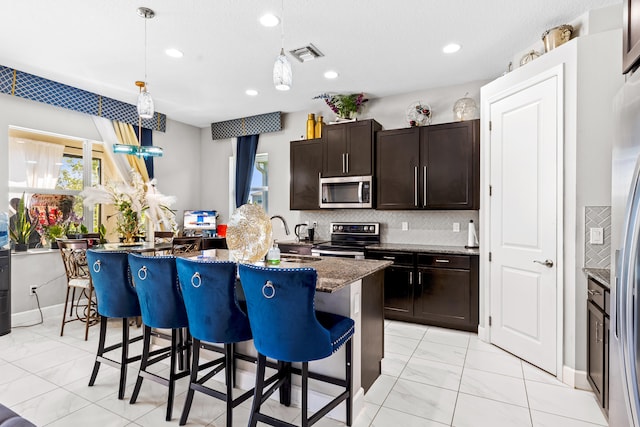 kitchen with a kitchen breakfast bar, tasteful backsplash, visible vents, and appliances with stainless steel finishes