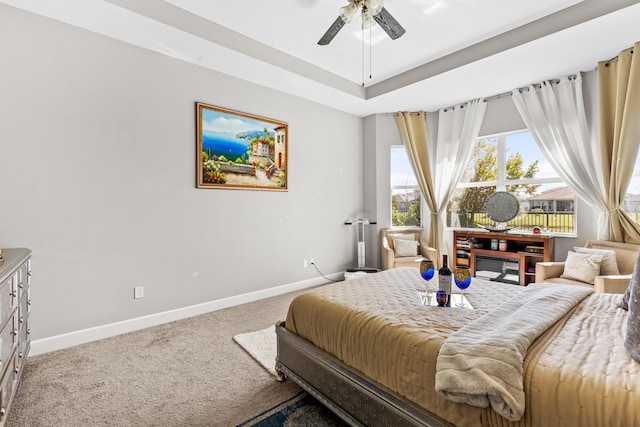 bedroom featuring a tray ceiling, baseboards, carpet floors, and ceiling fan