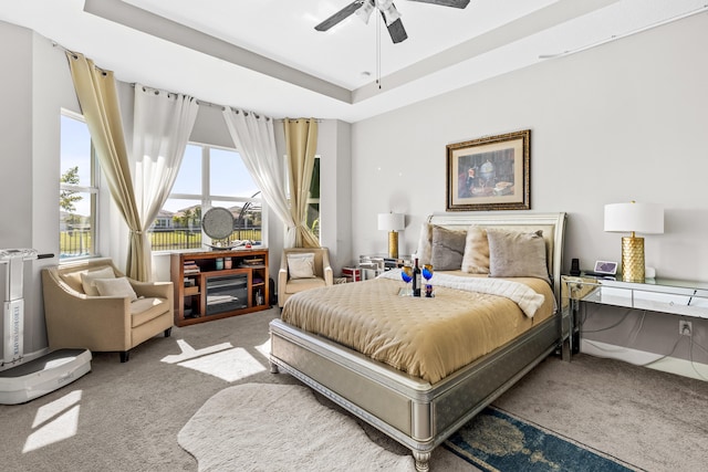 carpeted bedroom featuring ceiling fan and a tray ceiling