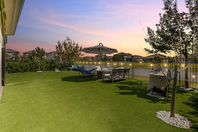 view of yard with an outdoor living space, a water view, and fence