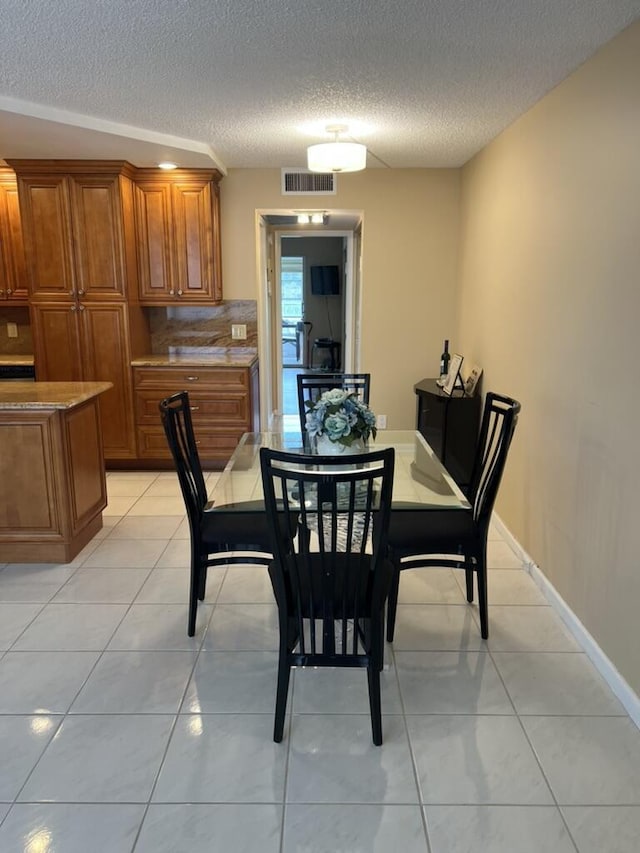 dining area with visible vents, baseboards, a textured ceiling, and light tile patterned flooring