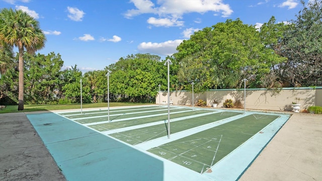 view of property's community featuring shuffleboard and fence