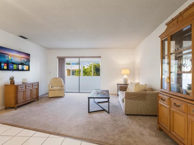 living area with light colored carpet, visible vents, and a textured ceiling