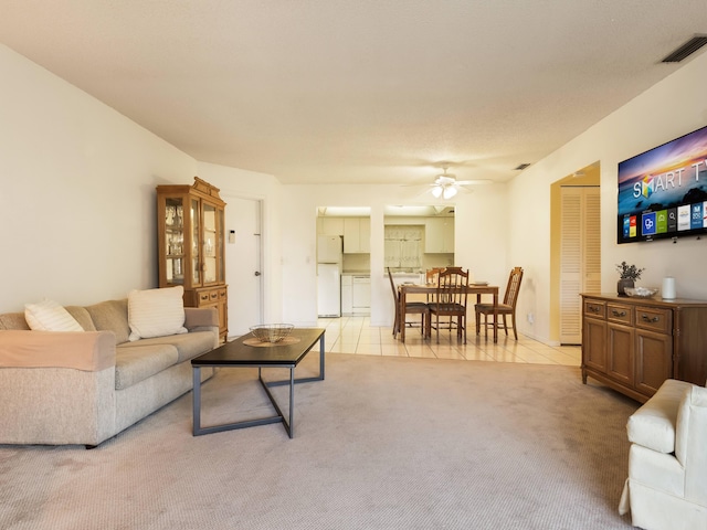 living area with light tile patterned floors, light colored carpet, visible vents, and ceiling fan