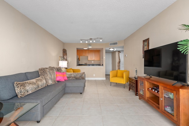 living area with light tile patterned floors, visible vents, rail lighting, and a textured ceiling