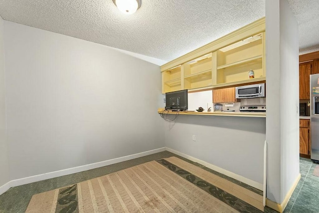 kitchen featuring a textured ceiling, open shelves, appliances with stainless steel finishes, and baseboards