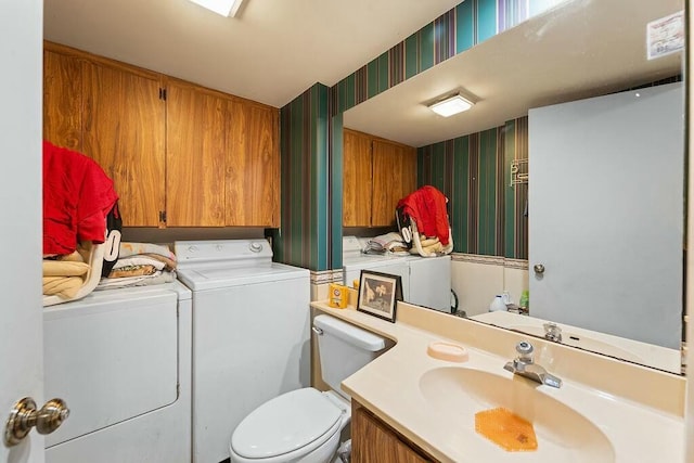 bathroom with toilet, wallpapered walls, washer and dryer, and vanity