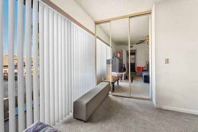 hallway with a textured ceiling, carpet flooring, and baseboards