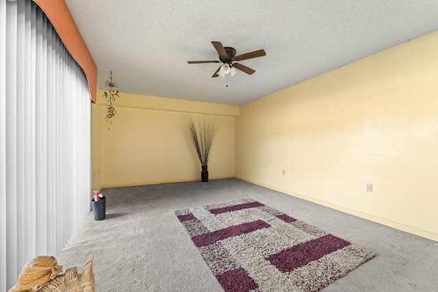 carpeted spare room featuring ceiling fan, baseboards, and a textured ceiling