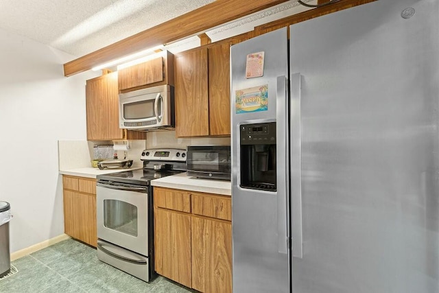 kitchen featuring stainless steel appliances, light countertops, and baseboards