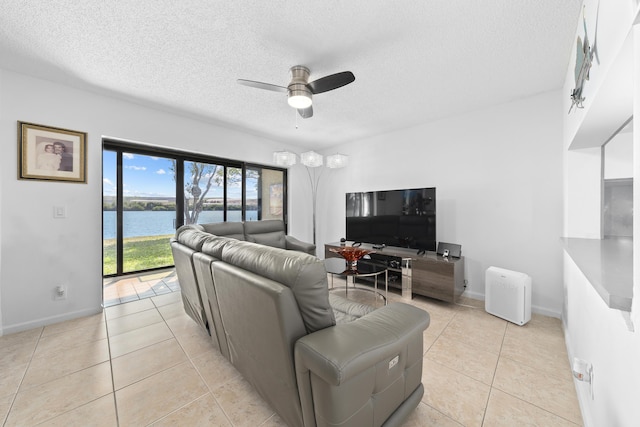 living area with ceiling fan, light tile patterned floors, baseboards, and a textured ceiling