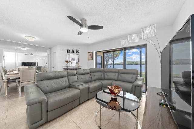 living room featuring light tile patterned floors, a textured ceiling, and a ceiling fan