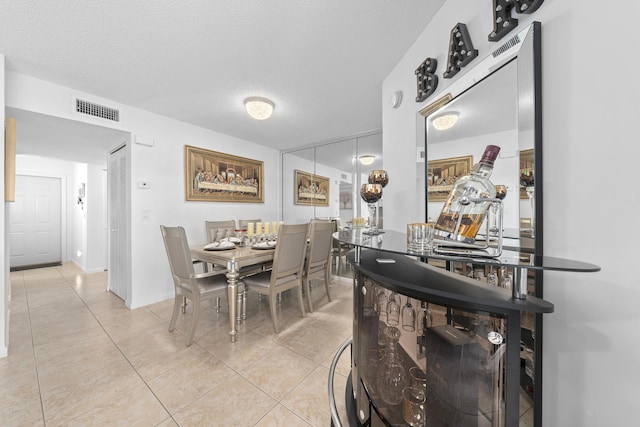 dining area featuring light tile patterned floors, baseboards, visible vents, and a textured ceiling