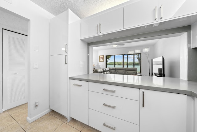 kitchen with light tile patterned floors, white cabinetry, and a textured ceiling