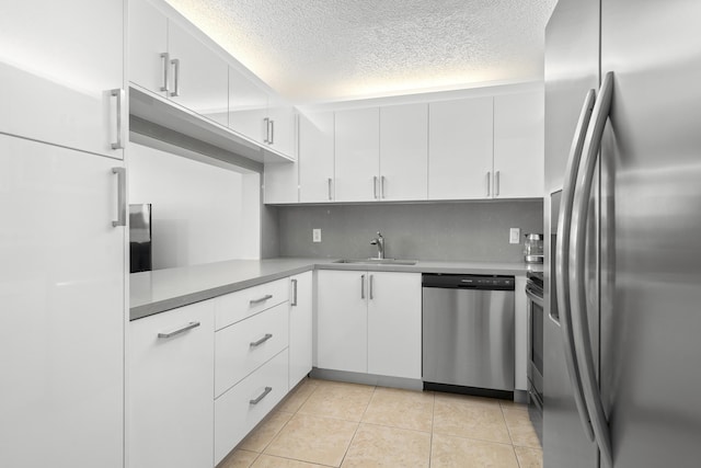 kitchen with tasteful backsplash, light tile patterned floors, appliances with stainless steel finishes, white cabinets, and a sink