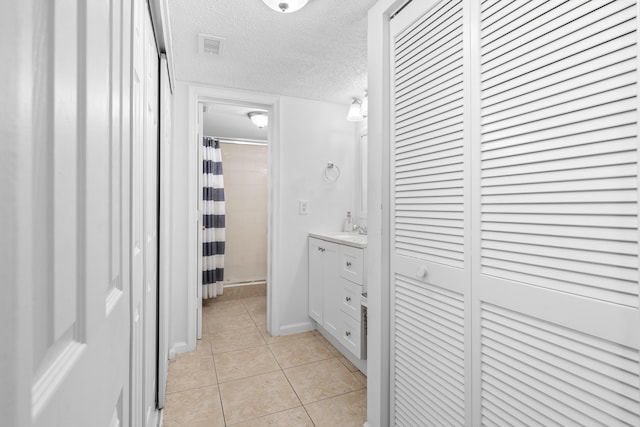 bathroom featuring vanity, a closet, a textured ceiling, curtained shower, and tile patterned floors