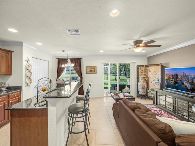 kitchen featuring visible vents, a breakfast bar, open floor plan, crown molding, and light tile patterned floors