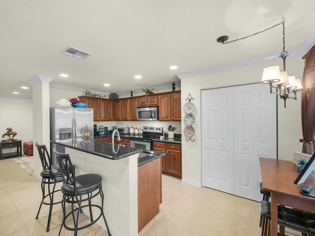 kitchen featuring light tile patterned floors, visible vents, appliances with stainless steel finishes, crown molding, and a kitchen breakfast bar