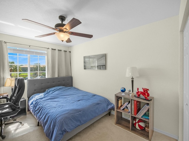 carpeted bedroom featuring baseboards and a ceiling fan