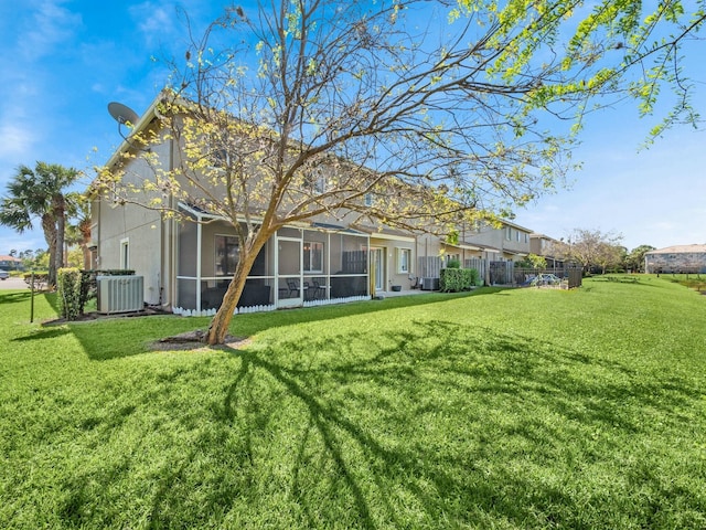 rear view of property with central air condition unit, fence, a yard, and a sunroom