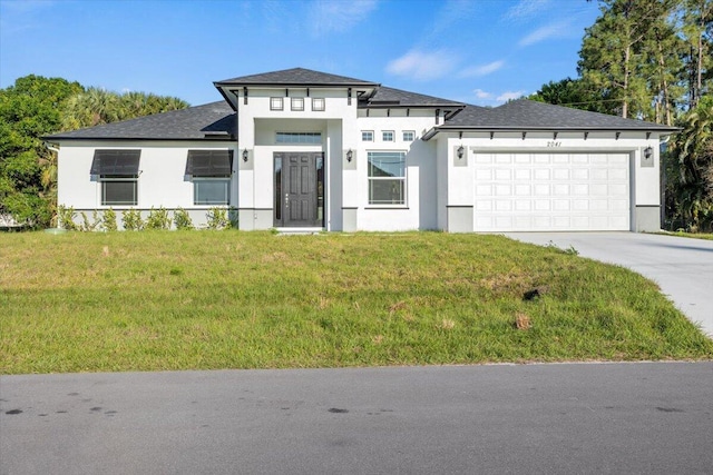 prairie-style home featuring a garage, concrete driveway, a front lawn, and stucco siding