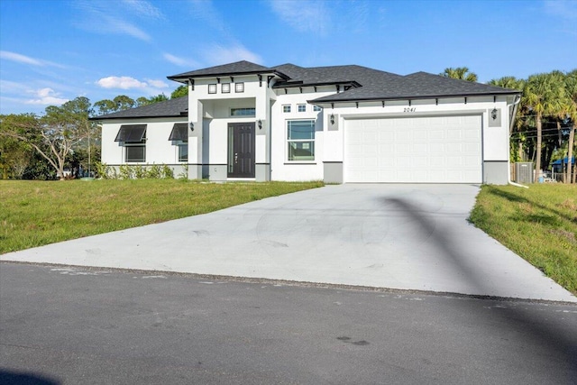 prairie-style home with central AC unit, stucco siding, driveway, a front yard, and a garage