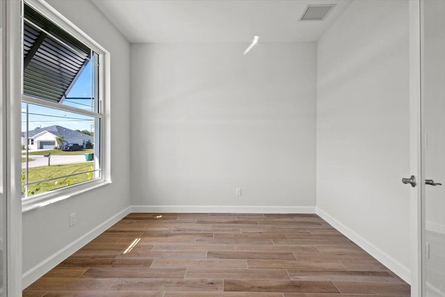 empty room with baseboards, wood finished floors, and visible vents