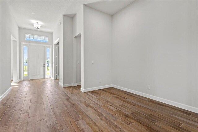 entryway with baseboards, wood finished floors, and a high ceiling