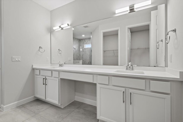 full bathroom featuring double vanity, a marble finish shower, a walk in closet, and a sink