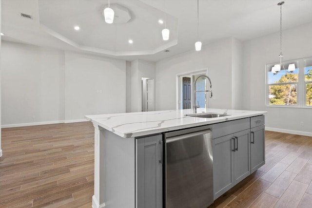 kitchen with a tray ceiling, light wood finished floors, gray cabinets, and a sink