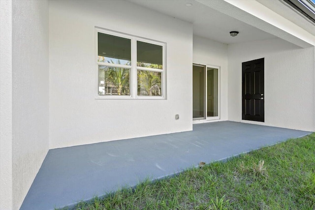 view of exterior entry featuring a patio and stucco siding