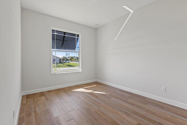 spare room with baseboards and wood finished floors