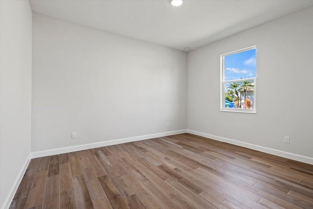 spare room with baseboards and wood finished floors