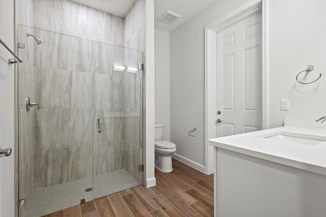 full bath with toilet, baseboards, wood finished floors, a shower stall, and vanity