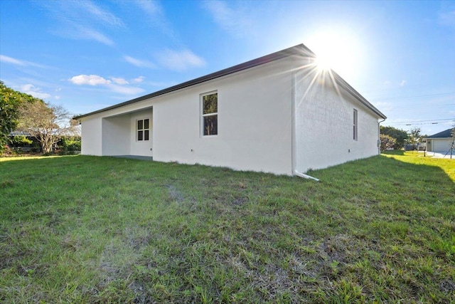 back of house featuring a lawn and stucco siding