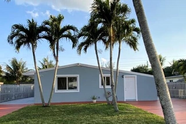 view of front facade with stucco siding, a front lawn, and fence